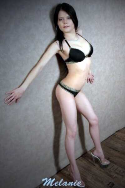 Das superschlanke Escort Girl Melanie steht mit Unterwäsche bekleidet super lasziv an einer Wand